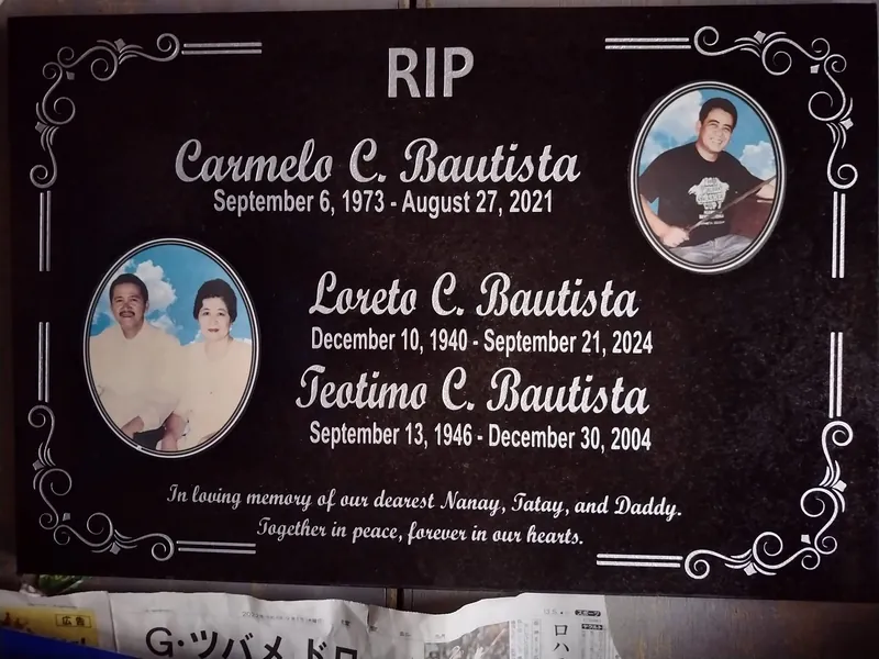 Black granite lapida with two oval ceramic portraits and silver script lettering for a family memorial
